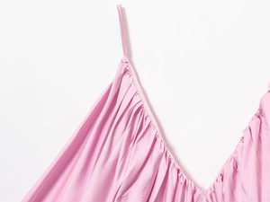 Detailed close-up of pink satin dress featuring delicate thin straps and pleated neckline