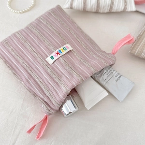 Detailed shot of striped drawstring storage bag with pink ribbons and logo tag