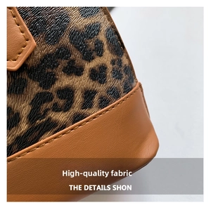 Macro shot of leopard print shell bag with brown leather trim and neat stitching