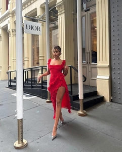 Detail of red square neck dress featuring high side slit and elegant ruffle trim