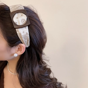 Close-up of beige cashew flower pattern headband with vintage brown buckle on a model