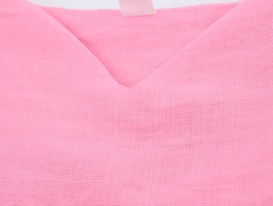 Dettaglio dello scollo a V e del tessuto rosa testurizzato di un abito estivo francese