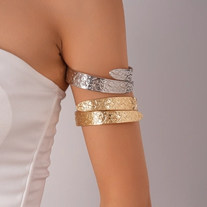 Close-up of gold and silver spiral arm cuffs with intricate vine patterns on female arm