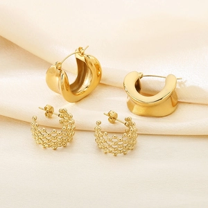 Golden 18K plated C-shaped hoop earrings and hollow mesh woven earrings on satin background