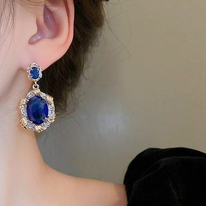 Close-up of vintage oval blue zircon earring with gold and silver rope texture on ear