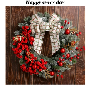 Detail of Christmas wreath with red berries, gold leaves and green plaid ribbon bow