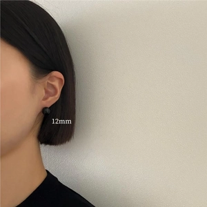 Detail showing a 12mm black sphere stud earring worn on ear with minimalist style
