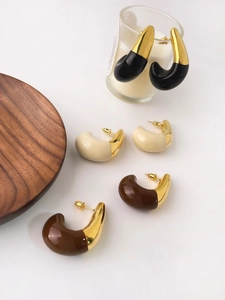 Close-up of 18K gold-plated teardrop C-shape earrings in black, white and brown resin