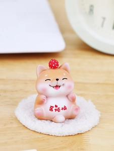 Miniature Shiba Inu dog figurine with strawberry hat on a cozy white plush mat