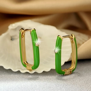 Detailed macro view of U-shaped gold hoop earrings with green enamel and zircon stones