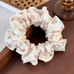 Close-up of floral scrunchie featuring delicate lace texture and pink flower patterns
