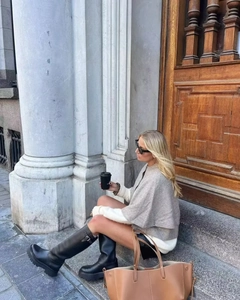 Chic grey knit poncho styled with tall black leather boots and a brown tote bag