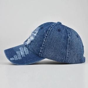 Detailed left-side view of distressed dark blue denim baseball cap with frayed edge finish