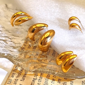 Three sizes of 18K gold teardrop earrings on textured glass and white fabric