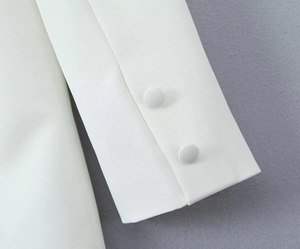 Close-up of white blazer sleeve featuring premium fabric-covered buttons and fine texture