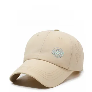 Detail of laser-cut ventilation holes and embroidered logo on beige baseball cap