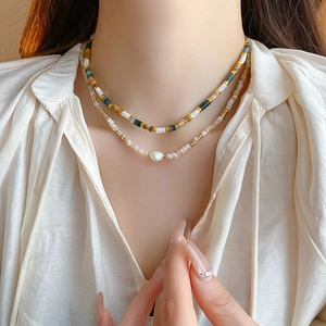 Double-layered beaded necklace featuring baroque pearls on a model wearing silk attire
