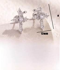 Macro detail of silver snake wrapped cross earring with pave-set cubic zirconia stones