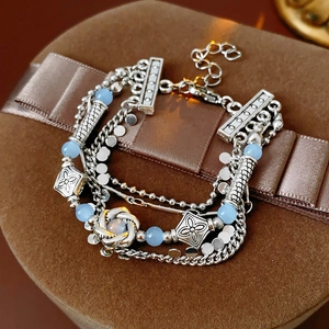 Detail of silver multi-layer bracelet featuring light blue beads and floral charms