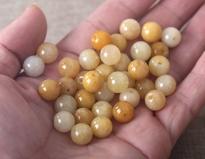 Close-up of polished natural yellow jade beads for DIY jewelry making held in hand