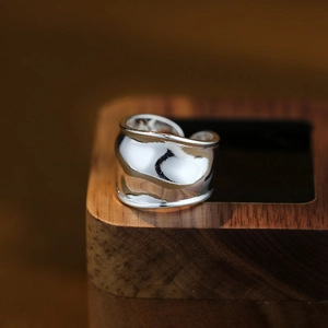 Anello largo a spirale in argento lucido dal design minimalista su base di legno