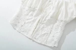 Detailed view of white lace patchwork and ruffled fabric with tie-up design on top