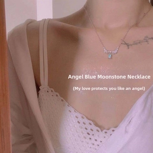 Detail of angel wing necklace with blue moonstone worn on a woman's collarbone