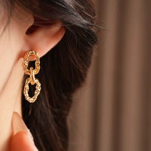 Détail de boucles d'oreilles en chaîne dorée aux formes ovales sur mannequin