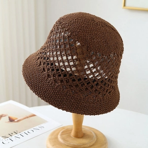 Detail of dark brown crochet bucket hat with hollow mesh design on a wooden stand