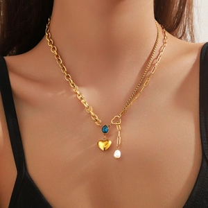 Gold layered necklace featuring blue teardrop zircon, heart pendant and pearl tassel detail