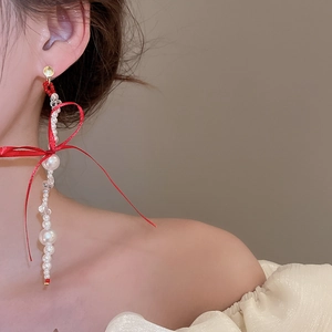 Elegant bow earrings featuring crystal ribbon with long cascading pearl tassels on a model