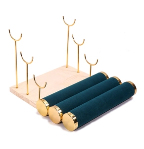 Detail view of the green velvet rollers and gold metal supports on jewelry display stand