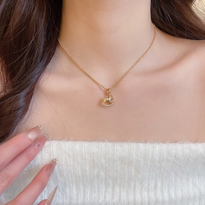 Close-up of gold plated rocking horse pendant necklace on model with white fleece