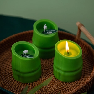 Bamboo shaped green scented candles set in a woven tray with a warm burning flame