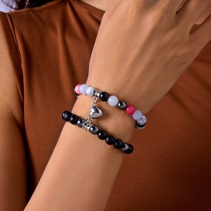 Detail of natural stone couple bracelets with magnetic heart charm on wrist