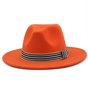 Dettaglio di un cappello fedora in lana arancione vivace con nastro a righe bianche e nere