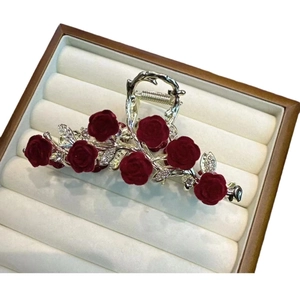 Elegant red velvet rose hair claw clip with rhinestones on beige velvet jewelry box