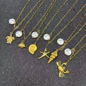 Selection of gold-plated starfish and shell necklaces with baroque pearls on black backdrop
