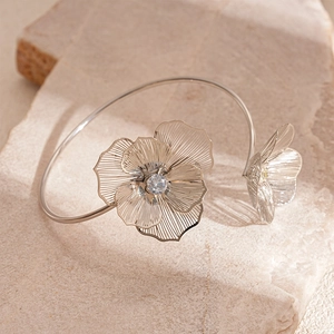 Détail d'un bracelet ajouré argenté avec fleurs et cristaux sur support en pierre