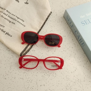 Detail of red oval sunglasses and blue light glasses set with UV400 protection