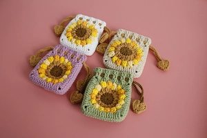 Flat lay of four handmade crochet sunflower drawstring pouches in pastel colors