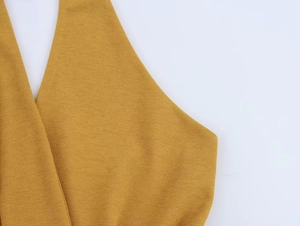 Vista macro del vestito allacciato al collo giallo zenzero con trama crepe e tessuto