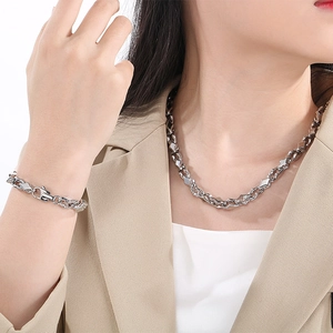 Close-up of geometric stainless steel necklace and bracelet set worn by a model