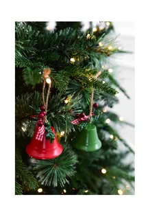 Close-up of red and green Christmas metal bells with pine needles and plaid bows on tree