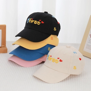 Detail of colorful embroidered letters and hearts on multi-colored cotton baby baseball caps