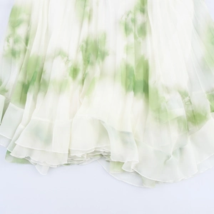 Bohemian pleated chiffon maxi skirt featuring a green tie-dye print on white fabric