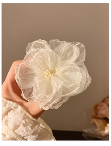 Detail of a large white layered organza flower hair clip with realistic stamens