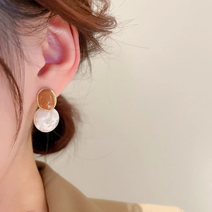 Detail of vintage round enamel drop earrings with gold rim on female model profile