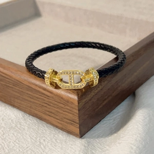 Dettaglio del bracciale in pelle nera intrecciata con fibbia dorata e micro-pave di diamanti