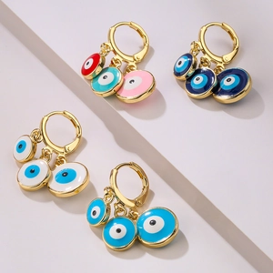 Set of four gold-plated evil eye hoop earrings with colorful enamel charms on stone steps